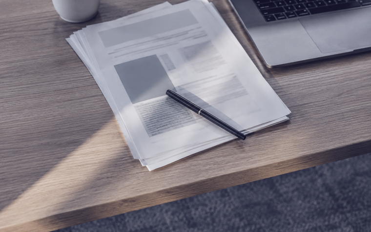 Stapel Ausdrucke und Notizen auf einem Schreibtisch